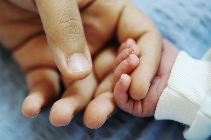 Hand van een volwassene met een babyhandje